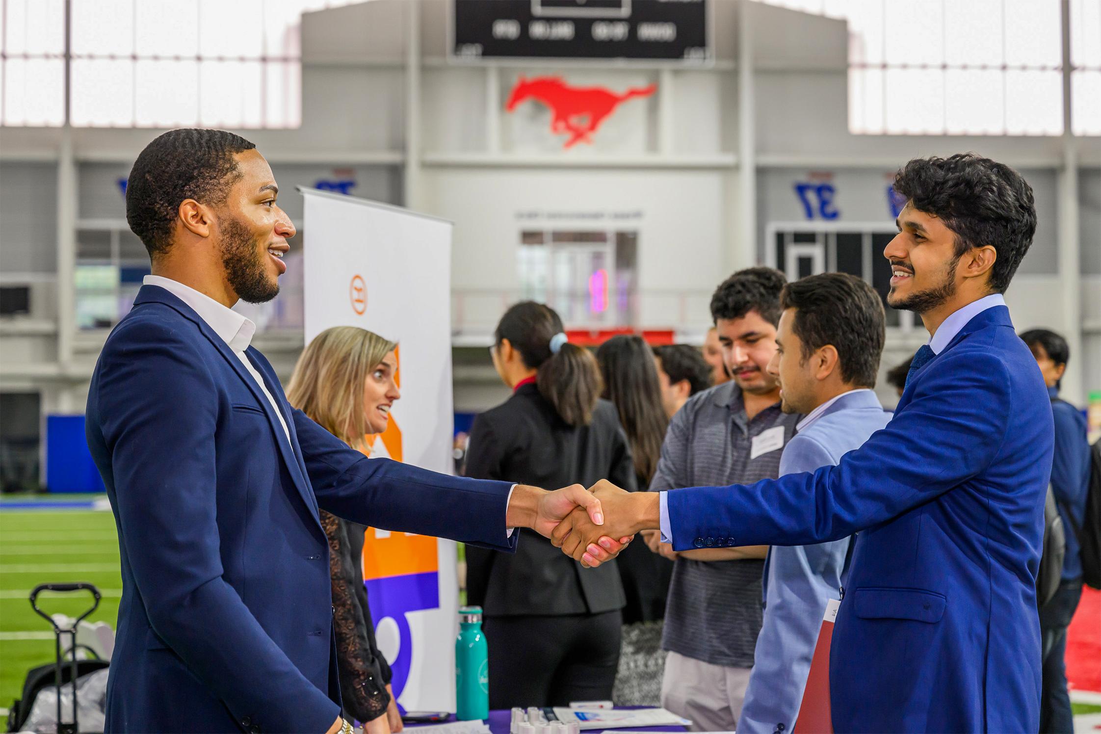 two men shaking hands in front of people talking